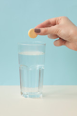 Glass with water on a white background with effervescent tablets vitamins. Vitamin C over blue background