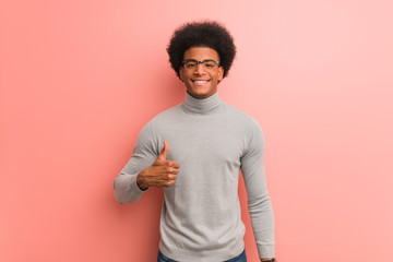 Young african american man over a pink wall smiling and raising thumb up