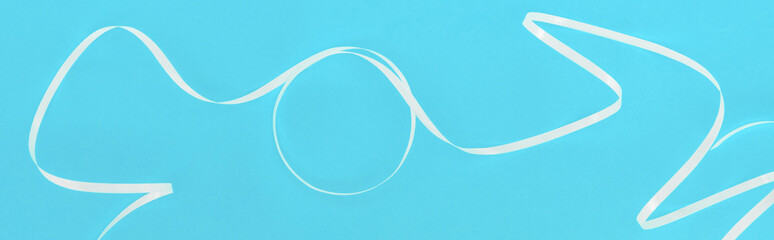 Panoramic shot of white ribbon on blue festive background