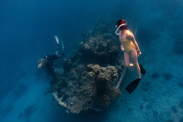 Young female free diver explores a shipwreck in a shallow water in Apo reef, Philippines.