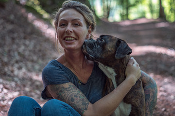 Junge Frau zusammen mit ihrem Hund im Wald, freudig lachend