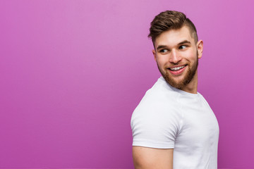 Young handsome caucasian man looks aside smiling, cheerful and pleasant.