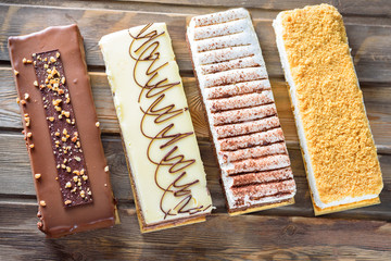 Beautiful Delicious dessert cheesecakes and chocolate cake on a rustic wooden table top view. Group of four different types of sweet for holiday Shavuot.