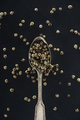 top view of spice in silver spoon on black background