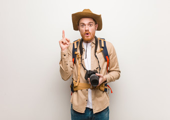 Young redhead explorer man having a great idea, concept of creativity. Holding a camera.