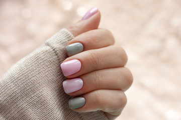 The pastel color manicure with the knitted sleeve of a brown sweater with glitter brown background