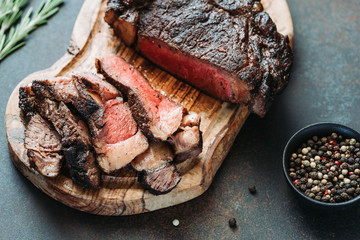 Dry-aged marble beef steak Tomahawk on wooden board with spices. Close-up, dinner concept.