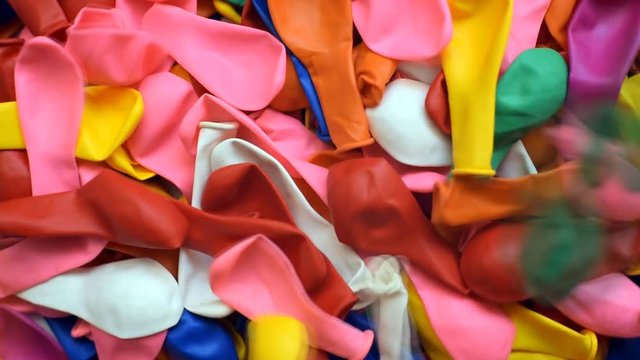 Many inflatable balloons of colors, deflated in a pile, colorful background