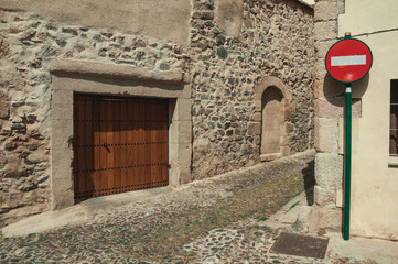 Wooden door on an old building facade and NO ENTRY traffic sign at Caceres