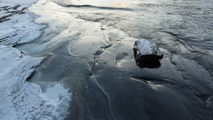 Fototapeta na wymiar Ice frozen over rocks in lake shore
