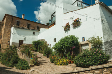 Fototapeta na wymiar House facade with white walls, stairs, flower pots and plants at Caceres
