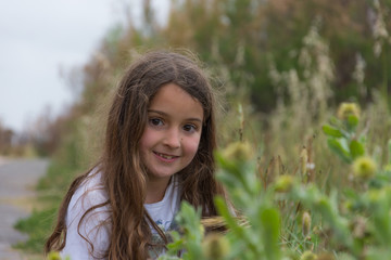 Naklejka premium Little girl smiling among the flowers