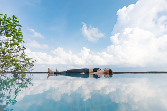 Vacation of Beautiful Attractive Asian woman relaxing in yoga Savasana pose on the pool above the beach with beautiful sea in Tropical island,Feeling comfortable and relax in holiday,Vacations Concept