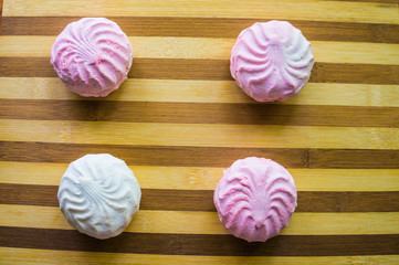 Pink and white marshmallows, four pieces on a bamboo board