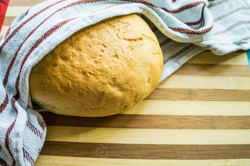White, freshly baked bread in a towel on a wooden board