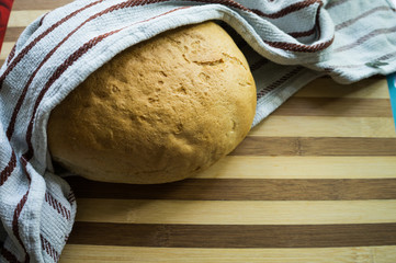 White, freshly baked bread in a towel on a wooden board