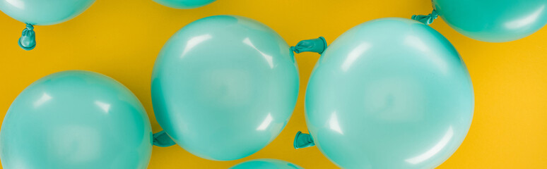 Panoramic shot of blue balloons on yellow background