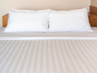 Fototapeta na wymiar Clean white bedding with four white pillows in hotel bedroom