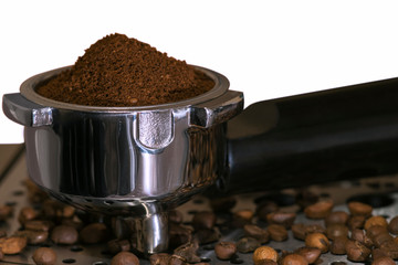 Ground coffee poured into a Cup for the coffee machine and scattered coffee beans near close-up on white background