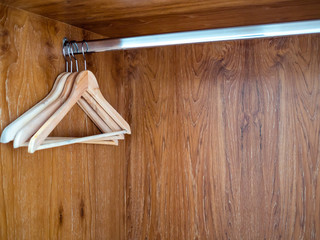 Naklejka na ściany i meble Wooden clothes hangers hanging on stainless steel bar in wooden clothes cupboard