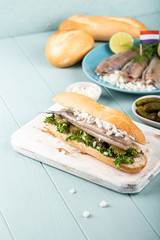 Traditional dutch snack, seafood sandwich with herring, onions and pickled cucumber. Broodje haring. Copy space.