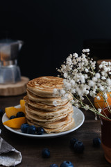 Beautiful rustic breakfast - pancakes with blueberries, peach, Gypsophila flowers, moka coffee machine, wooden table