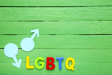 Abbreviation LGBT with gender signs on green wooden table
