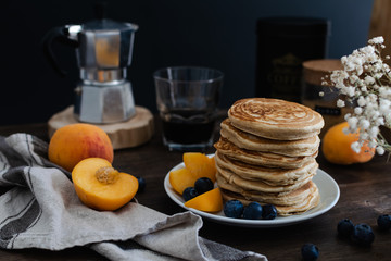 Beautiful rustic breakfast - pancakes with blueberries, peach, Gypsophila flowers, moka coffee machine, wooden table