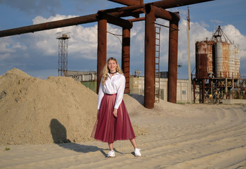 beautiful young girl on the background of industrial landscape and old construction equipment. portrait in grunge style. the concept of loneliness and the world of technology.