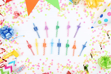 Happy Birthday candles with decorations on white wooden table