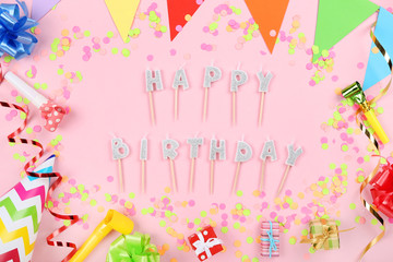 Fototapeta na wymiar Happy Birthday candles with party decorations on pink background