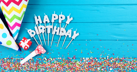 Happy Birthday candles with decorations and sprinkles on wooden table
