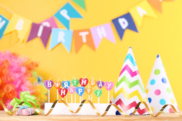 Happy Birthday candles with party decorations on yellow background
