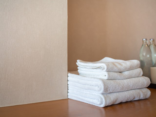 White clean towels on wooden surface and white wall background