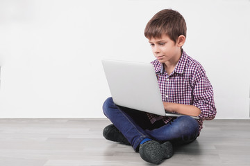 Child with laptop sitting on the floor,