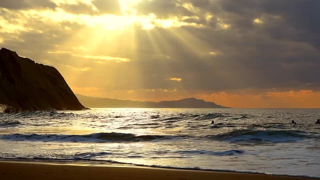 Golden sunset with sun's rays over the ocean. Itzurun beach, flysch of Zumaia on the coast of Gipuzkoa, Spain. Outdoor fitness lifestyle.
