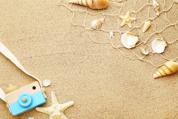 Seashells with fishing net and camera on beach sand