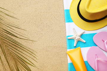 Flip flops with starfish, palm leaf and hat on beach sand