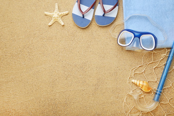 Fototapeta na wymiar Flip flops with seashells, diving mask and snorkel on beach sand