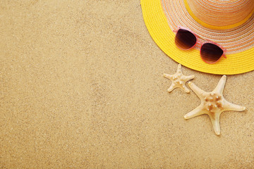 Fototapeta na wymiar Beach hat with starfishes and sunglasses on sand