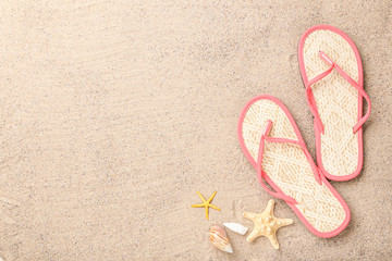 Fototapeta na wymiar Pair of flip flops with seashells on beach sand