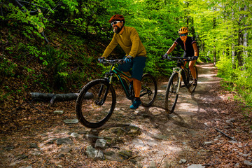 Cycling woman and man at Beskidy mountains autumn forest landscape. Couple riding MTB enduro track....