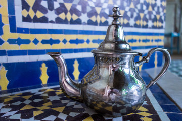 Silver metal tea kettle with mosaics background standing in a palace in Fez, Morocco