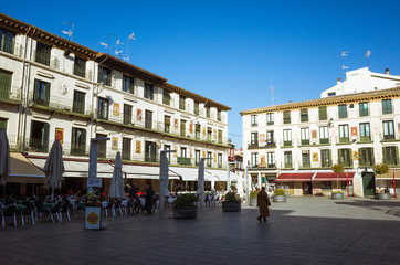 Fototapeta na wymiar Tudela, Navarre, Spain - February, 13th, 2019 : Passersby at the 17th century Plaza Nueva or Plaza de los Fueros square, decorated with the coats of arms of the towns in La Ribera region of Navarre.