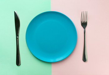 Empty blue plate fork and knife on duotone green pink background. Healthy diet meal planning concept. Mockup template. Creative foot poster with copy space