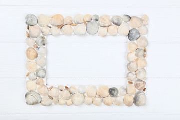 Wooden blank frame with seashells on white table