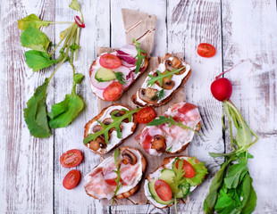 Bruschetta assortment with cream cheese, champignons, pancetta meat, vegetables and greenery
