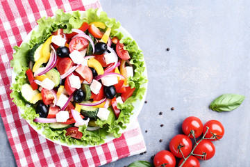 Vegetable salad in bowl with red napkin on grey background