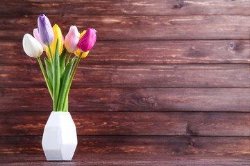 Bouquet of tulip flowers in vase on brown background