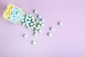 Colorful paper stars in glass jar on purple background